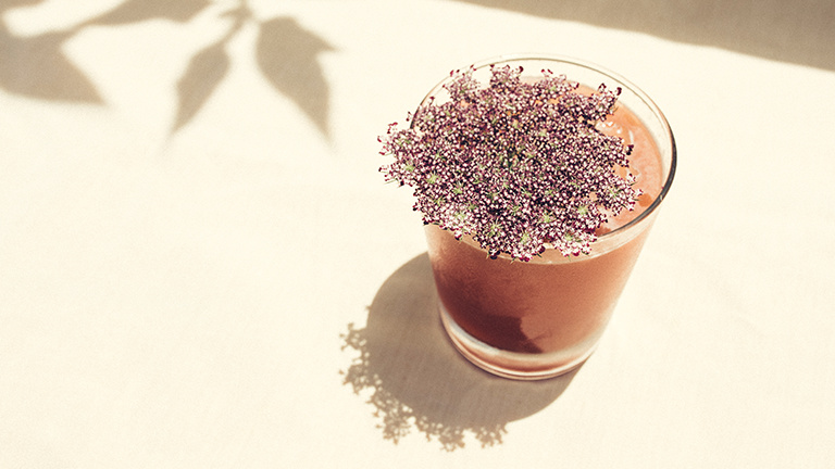 brown cocktail topped with a large flower on a white table cloth