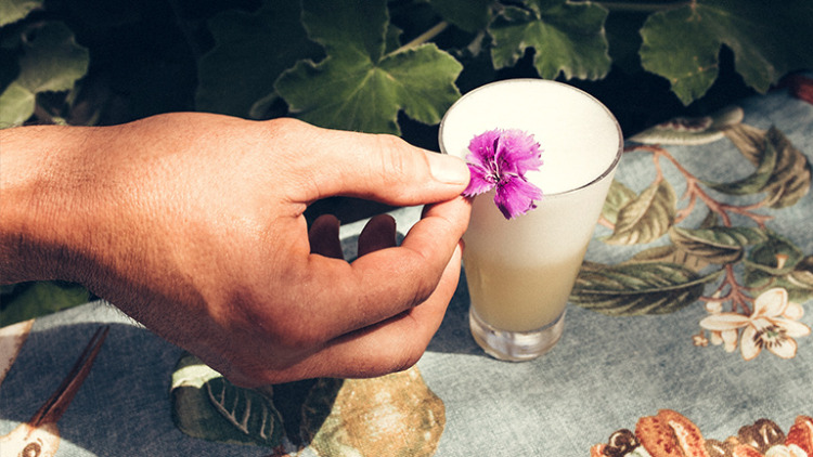 A cocktail placed on a patterned table cloth adorned with a floral top piece