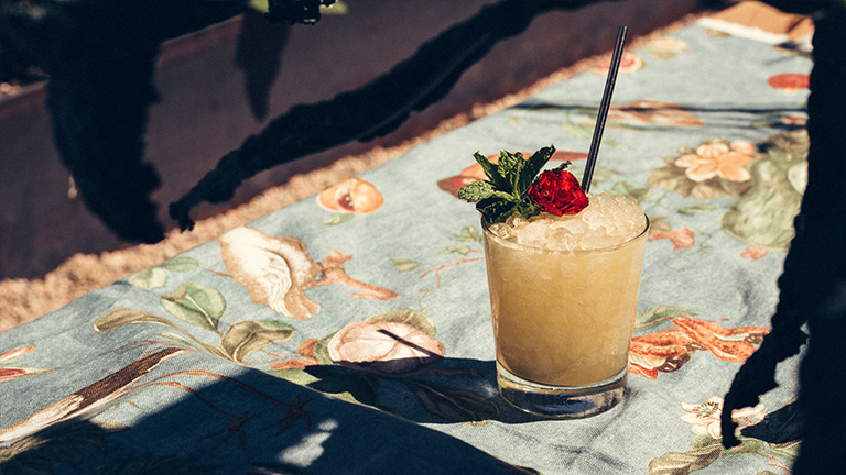 A cocktail placed on a patterned table cloth adorned with a floral top piece