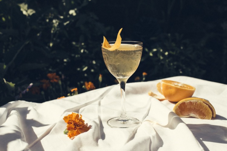 A cocktail placed on a white table cloth adorned with oranges