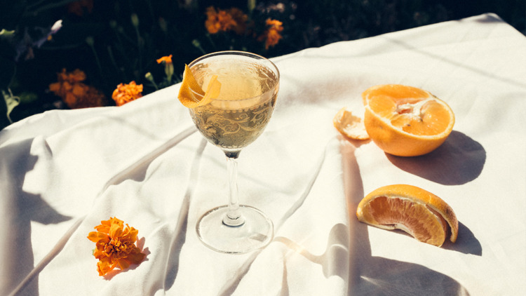 A cocktail placed on a white table cloth adorned with oranges