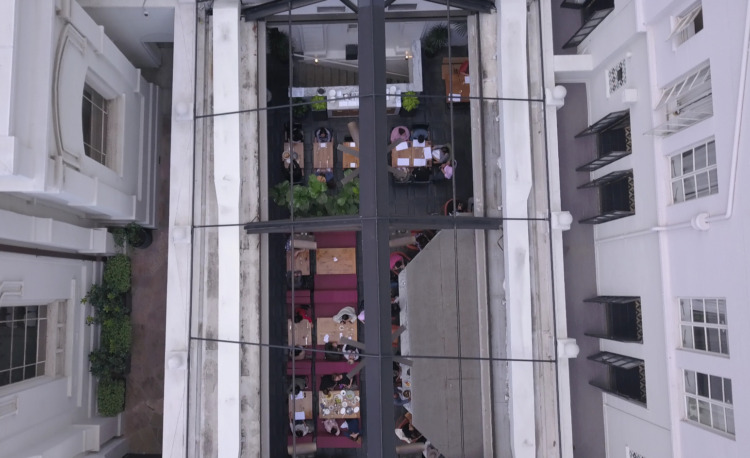 birds eye viewing looking down from outside at glass ceiling with diners eating inside