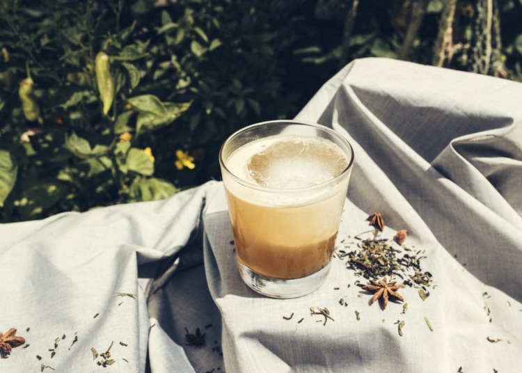 A cocktail placed on a white table cloth adorned with shrubbery