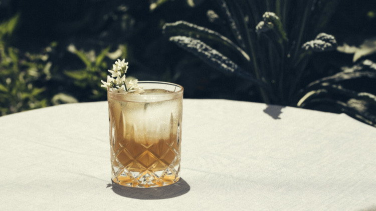 glass of honeysuckle cocktail on outdoor table