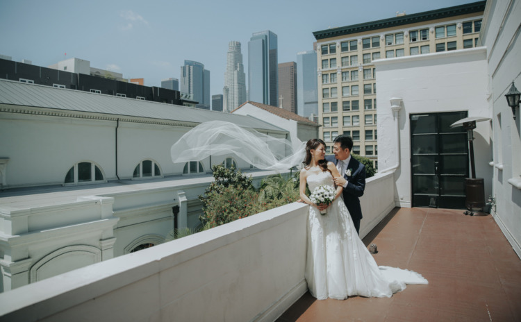 bride and groom on top floor patio with brides veil floating in the wind