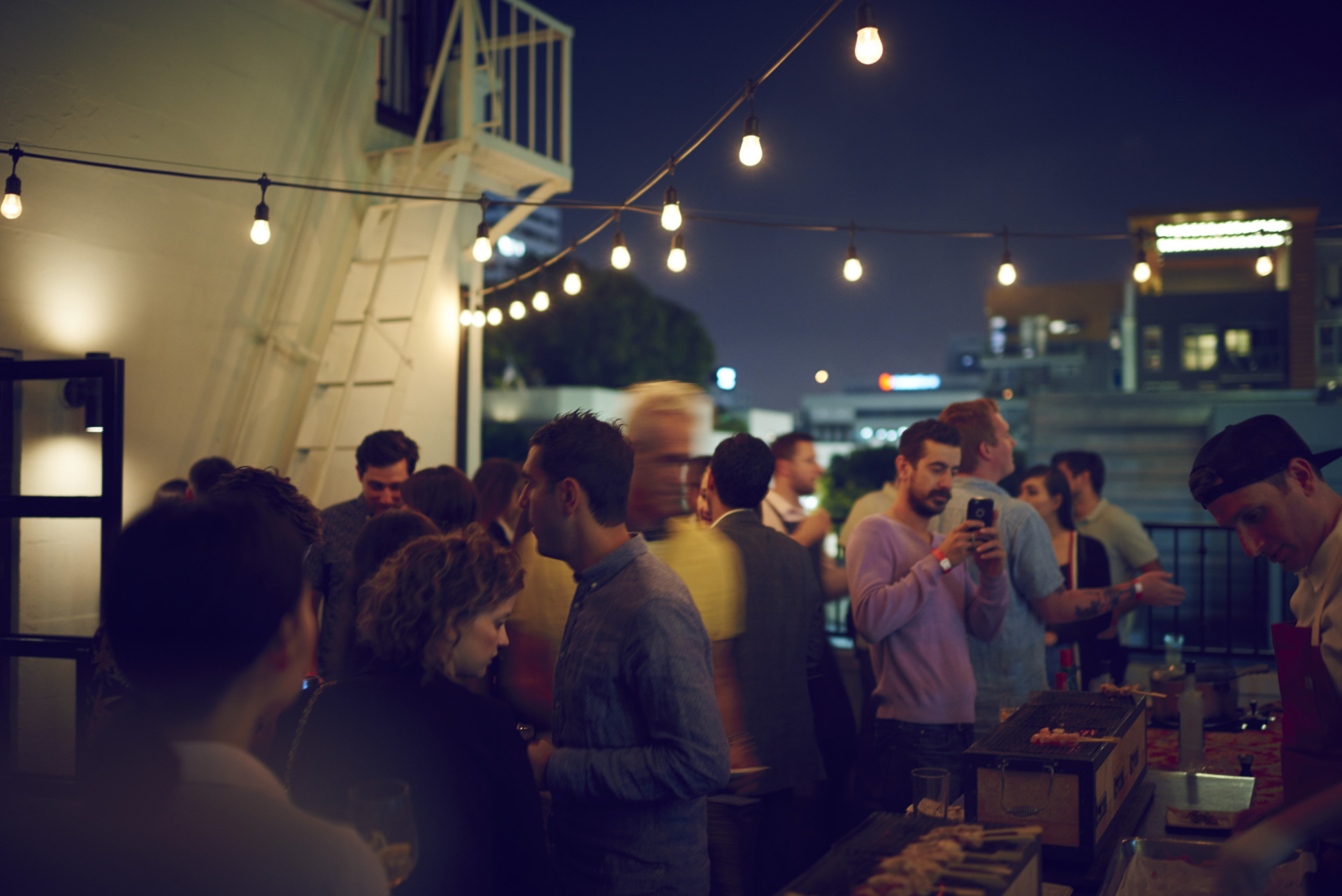 group mingling outside at night under string lights