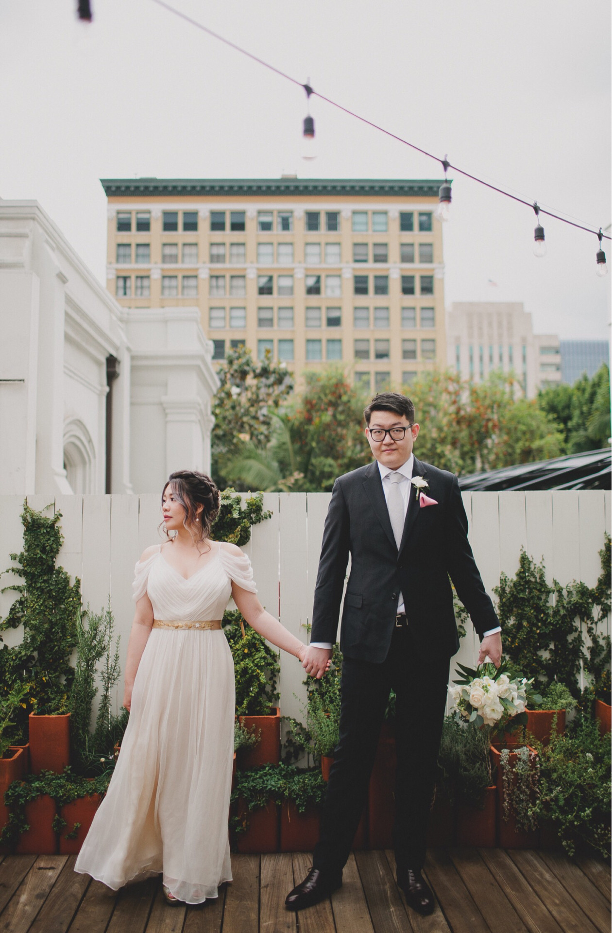 bride and groom outside on wooden patio holding hands