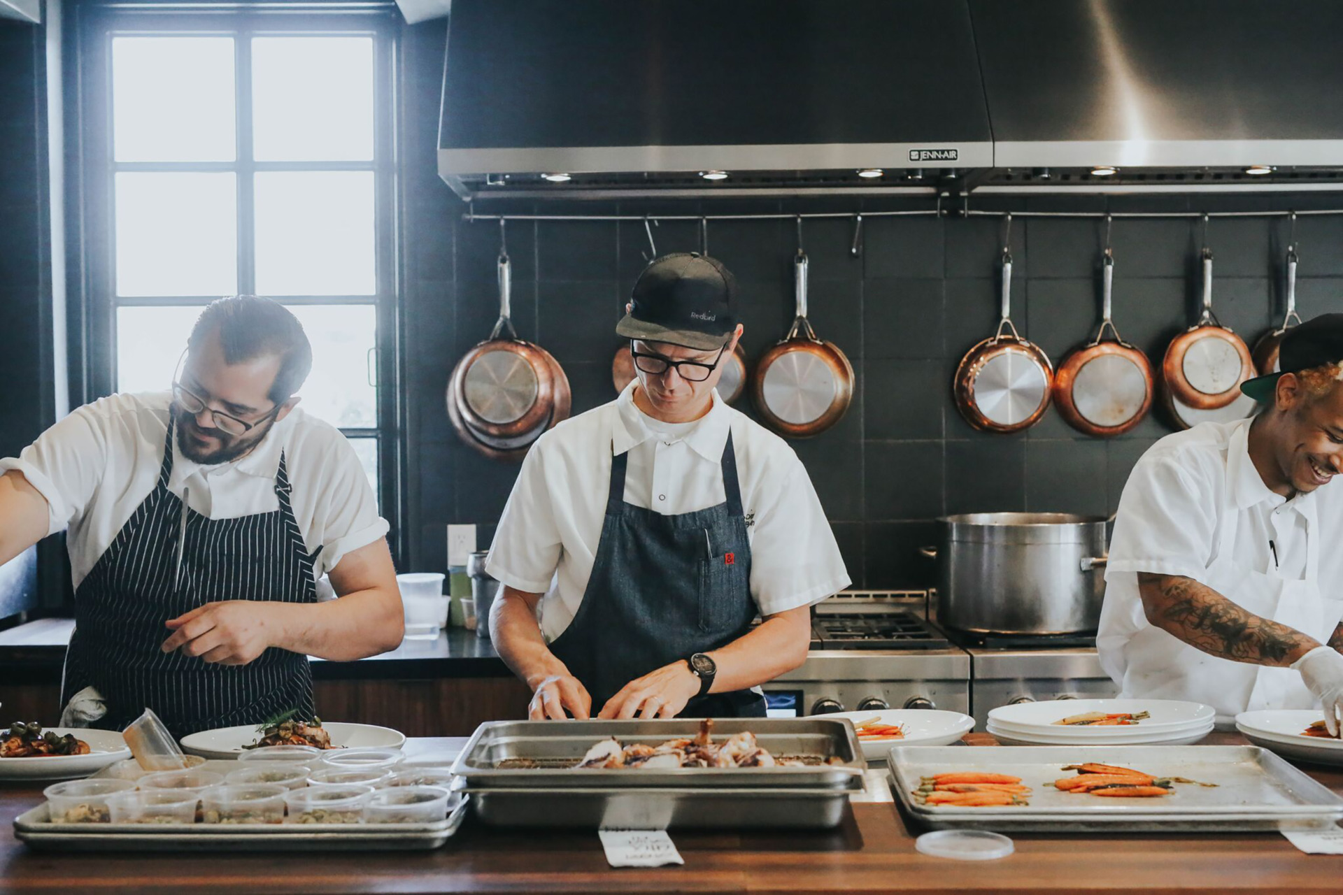 three chefs preparing plates in the kitchen