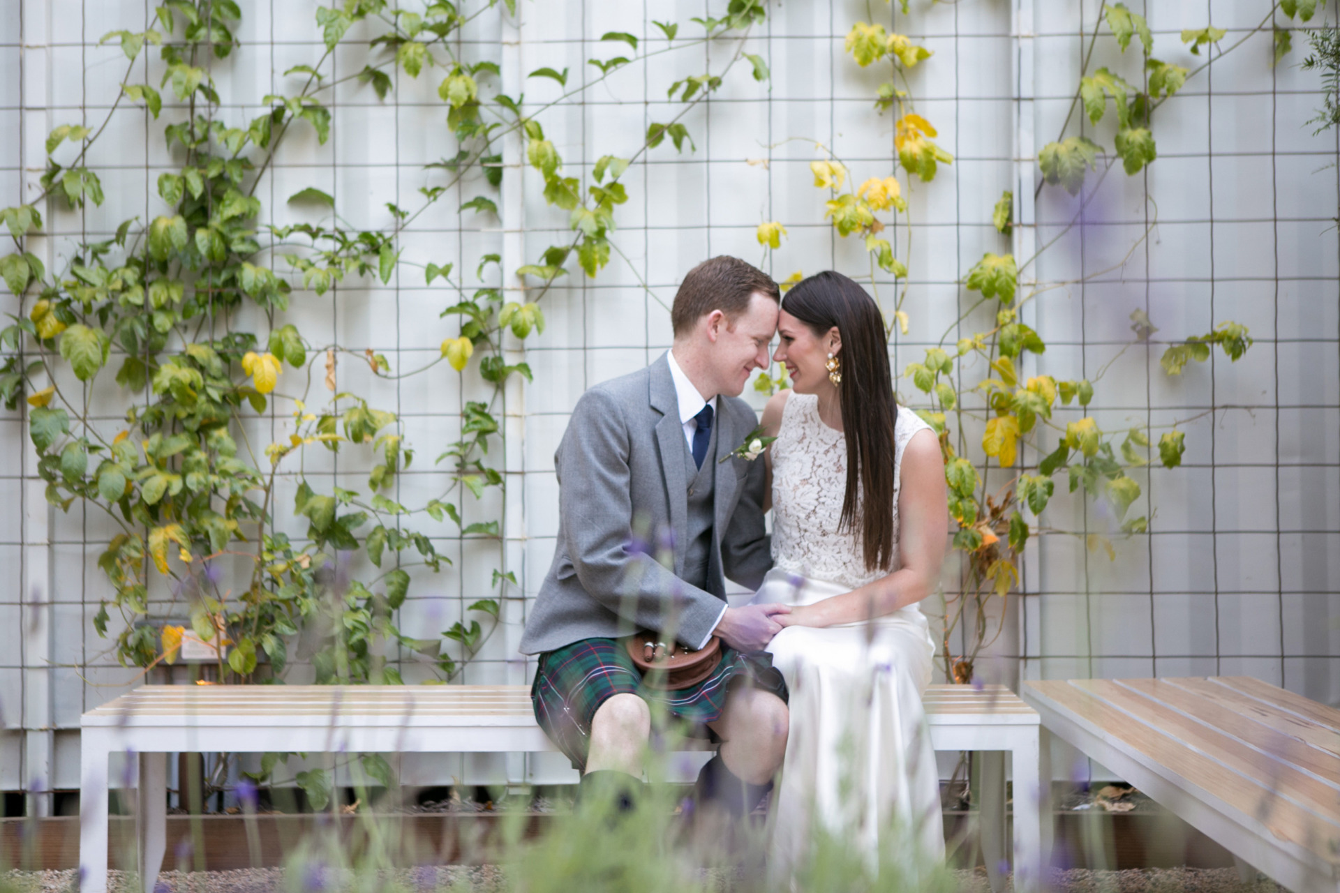 bride and groom seated on benches in garden