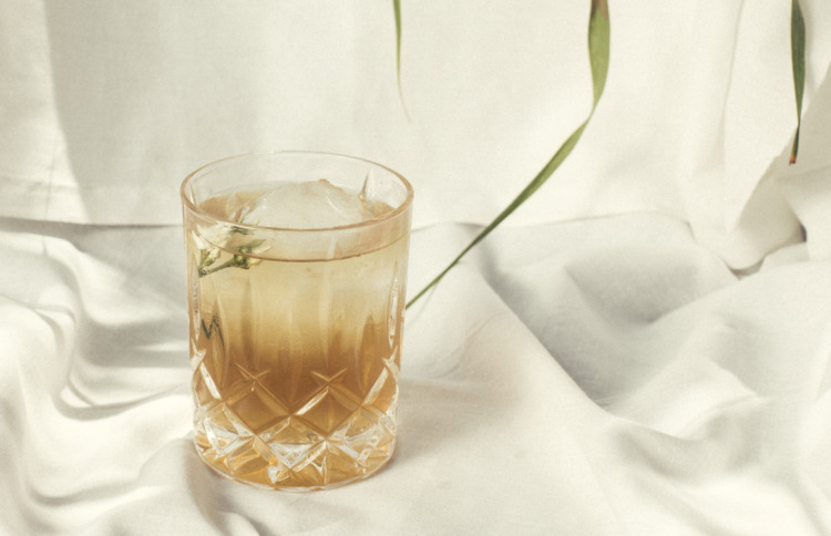 glass with honeysuckle cocktail on white cloth