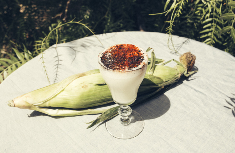 garden table set with spiced cocktail and a husk of corn