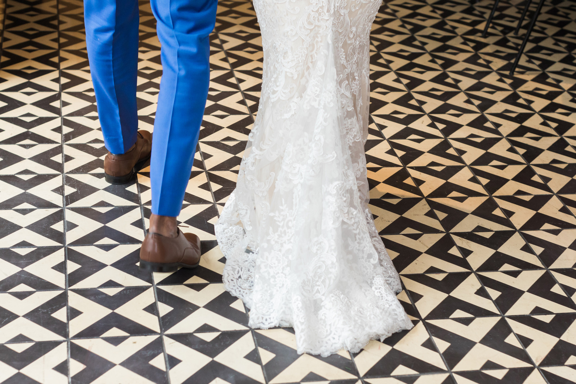 bride and grooms lower legs walking across back and white tiled floor