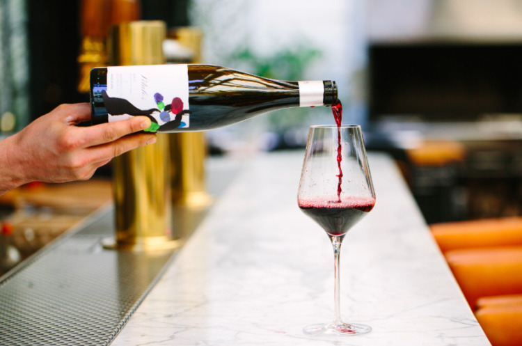 bartender pouring red wine into a glass