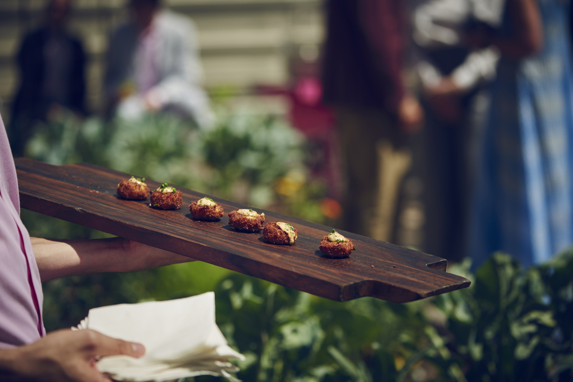 waiter holding wood tray with six pieces of hors d'oeuvres