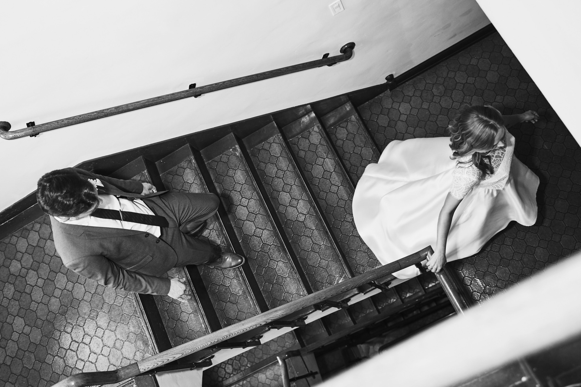 black and white shot of bride and groom walking down stairs