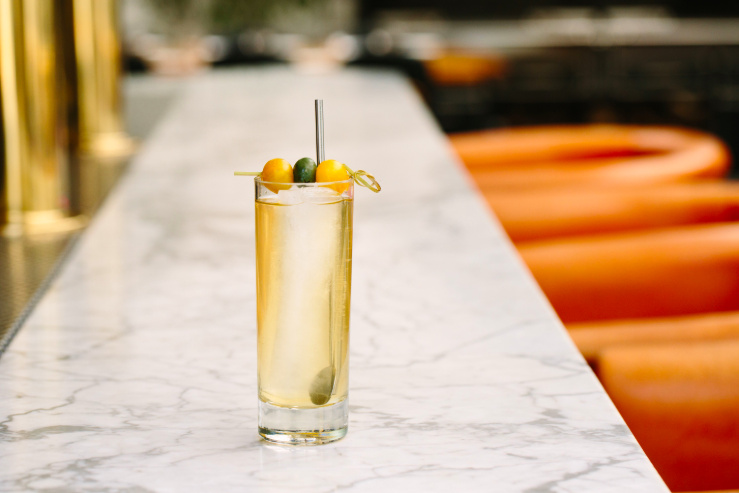 cocktail glass topped with fruit on a marble bar top