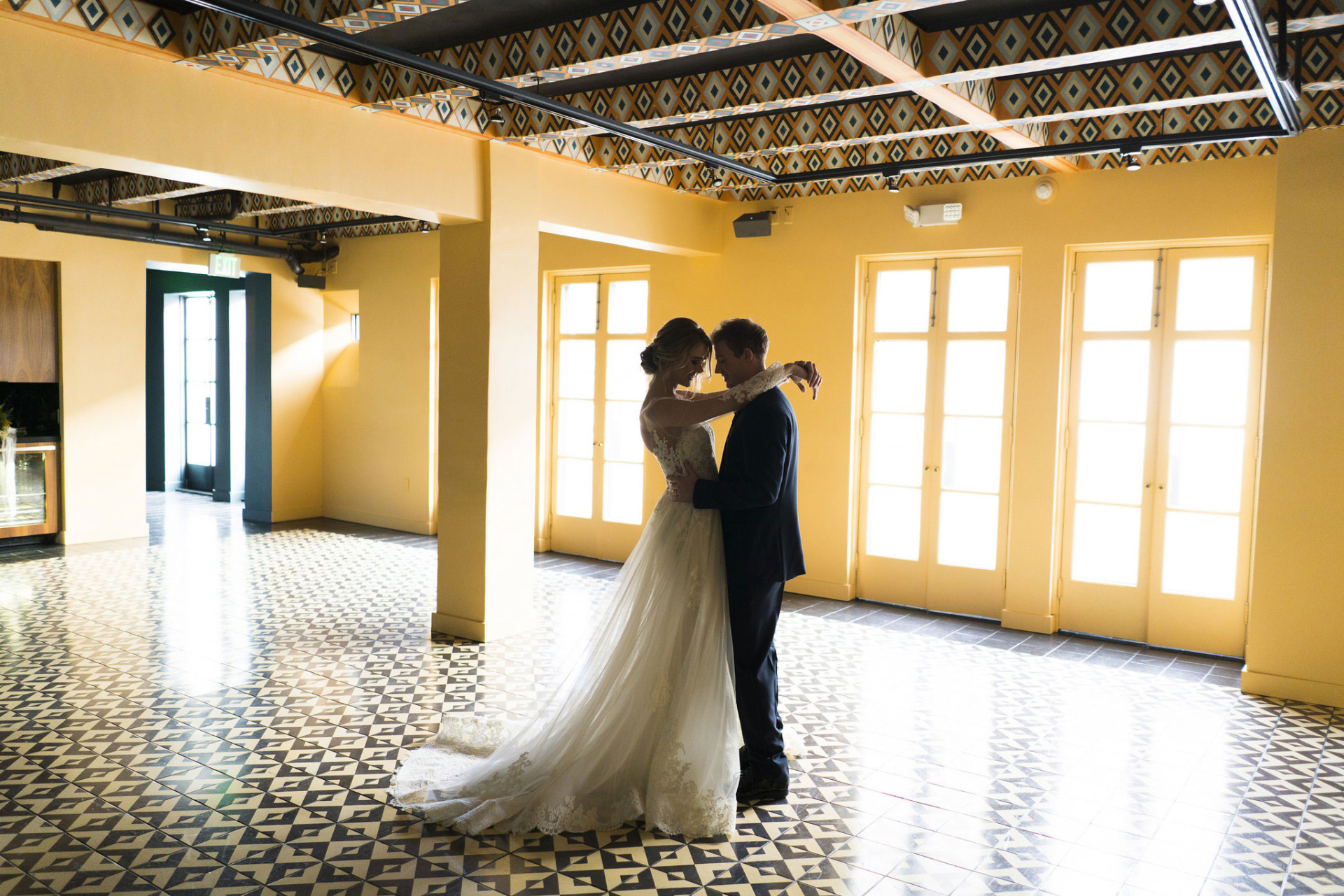 bride and groom dancing in colorful yellow room with painted ceiling and black/white tiled floor