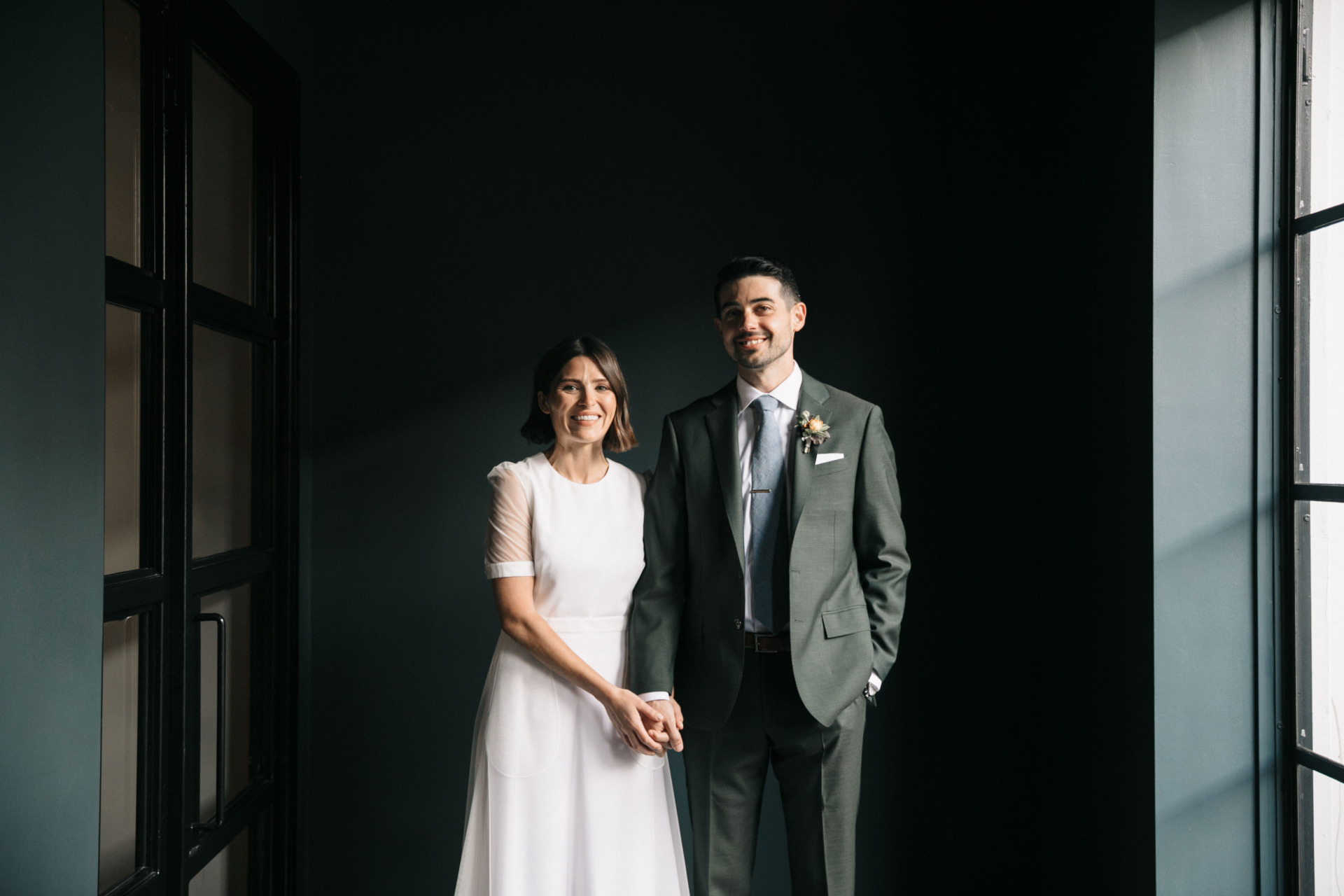 bride and groom smiling and holding hands with blue grey walls