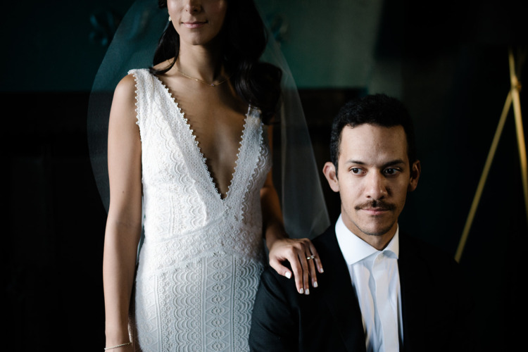 Bride holding the shoulder of sitting groom