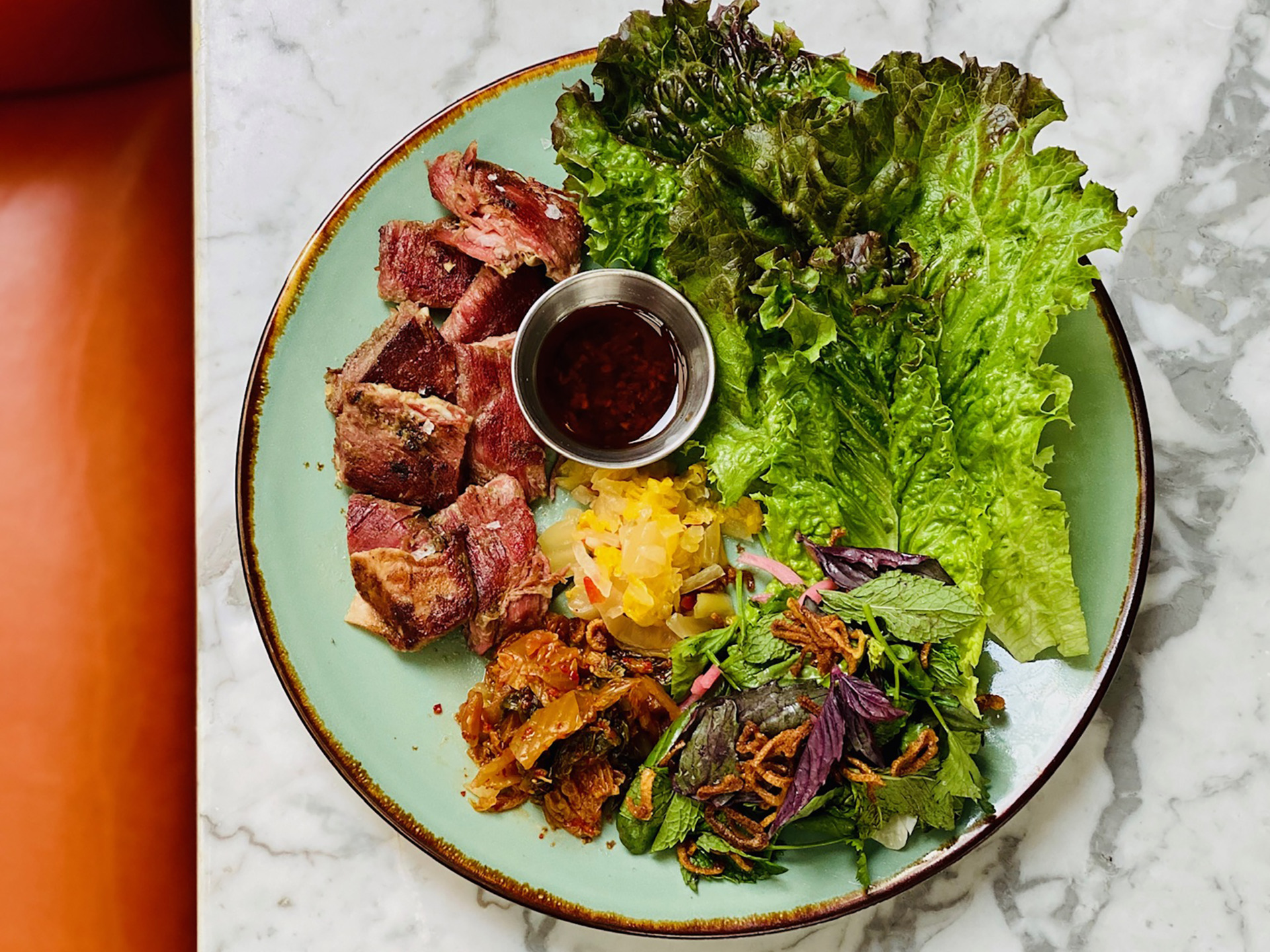 lamb belly with lettuce on a marble bar with orange stool