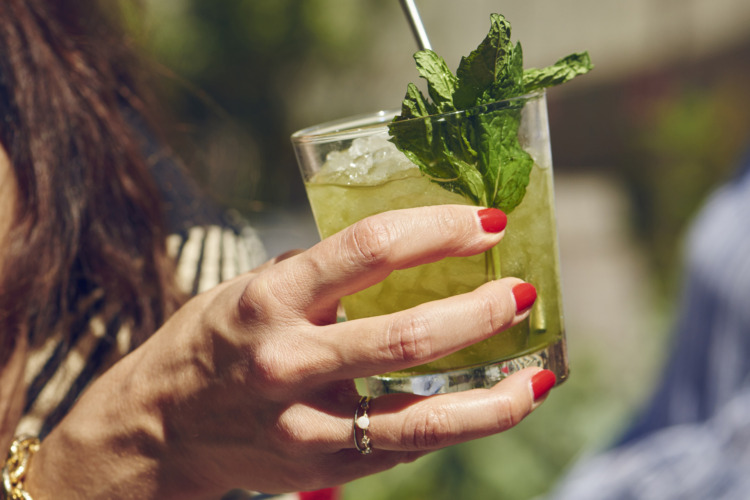 woman with red nail polish holding mint julep