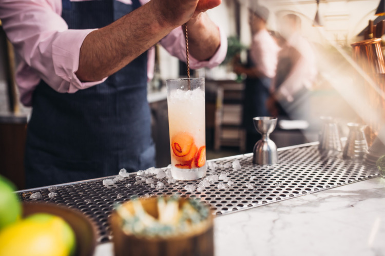 man's hands mixing a cocktail with strawberries