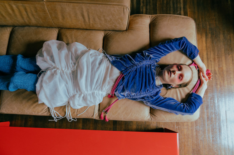 model in blue shirt lying on couch