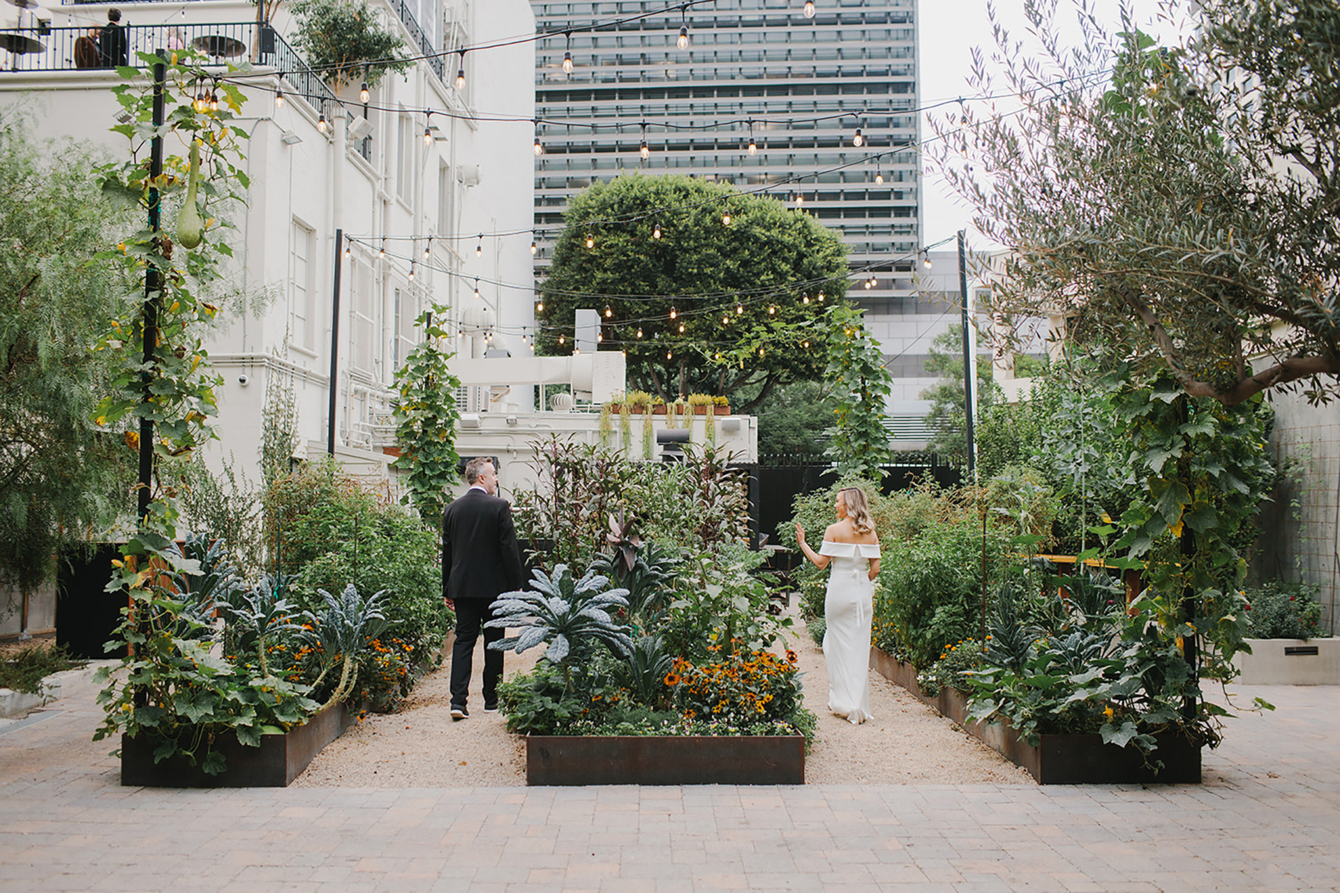 groom and bride walking through a garden