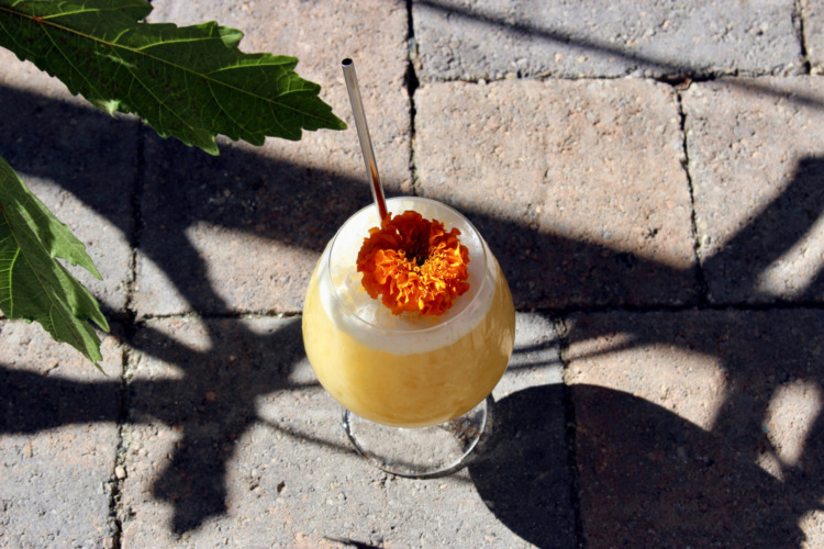 yellow cocktail with orange flower on the ground