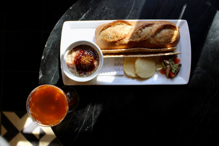 bread, butter, mousse and a cocktail in orange on a black table