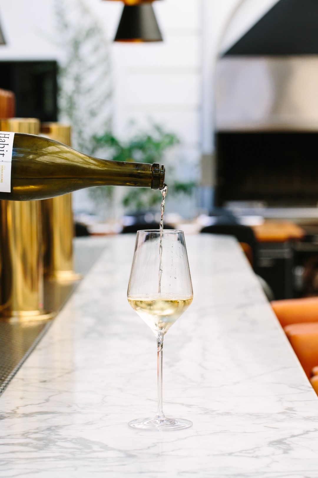 white wine being poured into a wine glass on the bar top