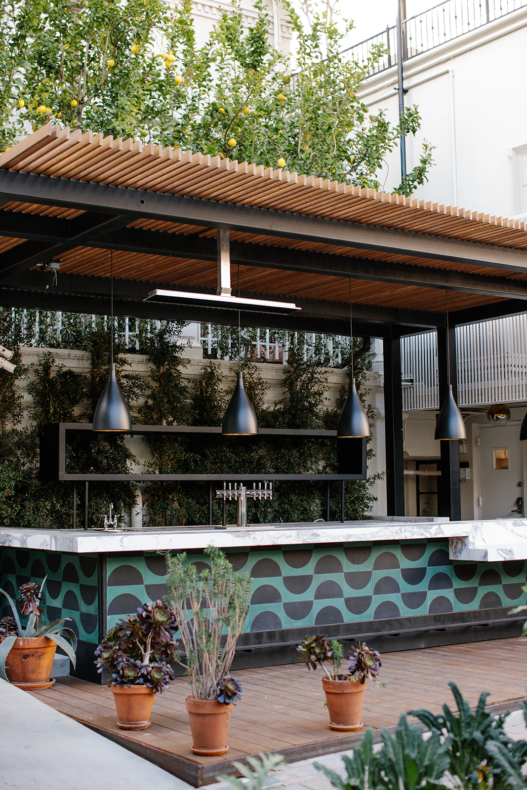 the Redbird Garden outdoor bar in DTLA, with teal and black patterns and overhead heaters and succulent plants