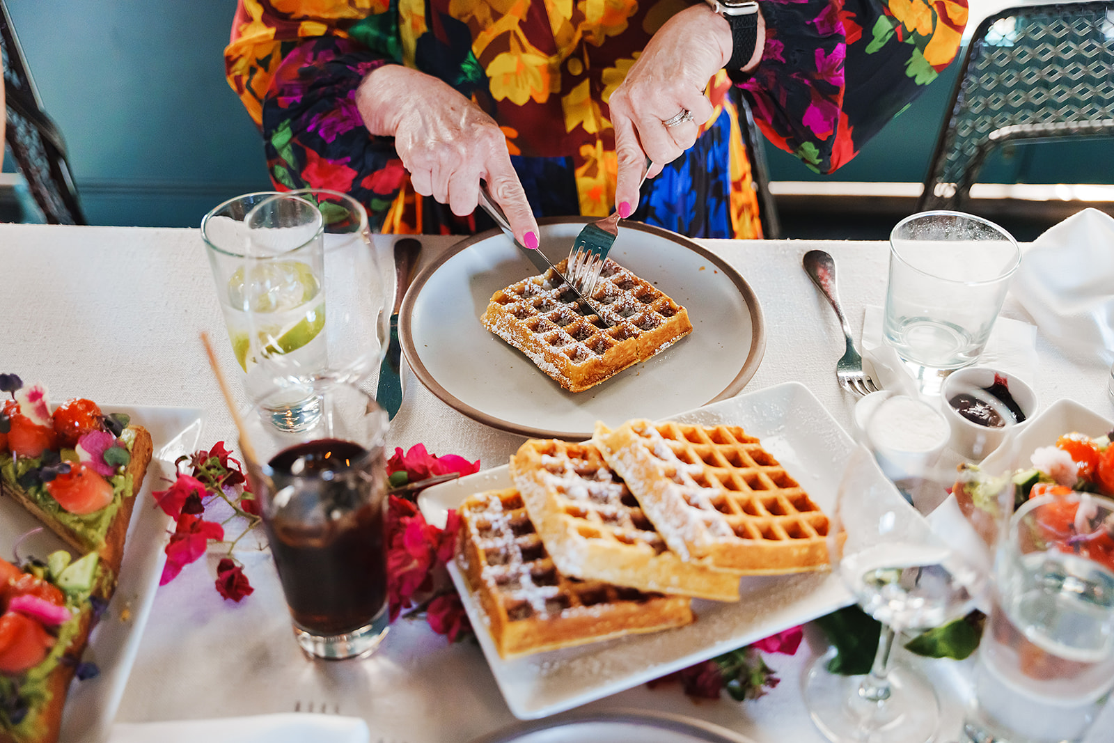 a guest cuts a slice of waffle on a breakfast plate in the Cardinal's Quarters at Redbird