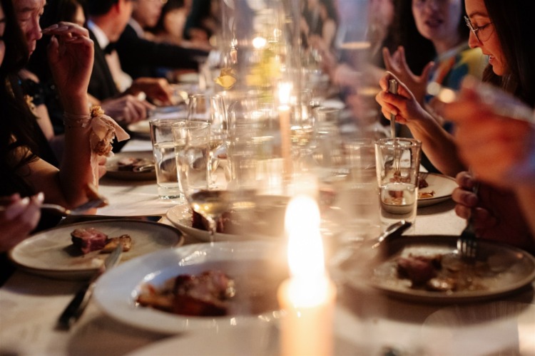 wedding guests at the Cardinal's Quarters venue at Redbird in Los Angeles eat their dinner