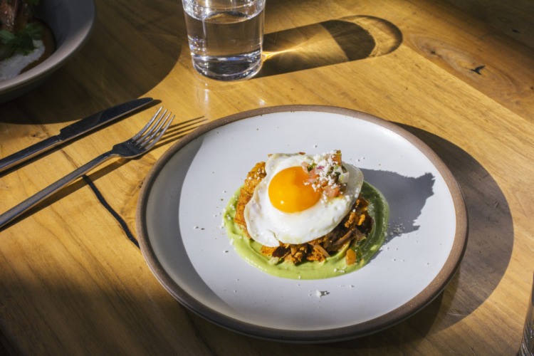 redbird's duck confit chilaquiles dish with a fried egg on top, sitting on a plate on a table