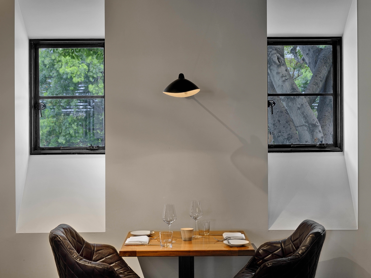 a table set for two in a restaurant with an overhead lamp above