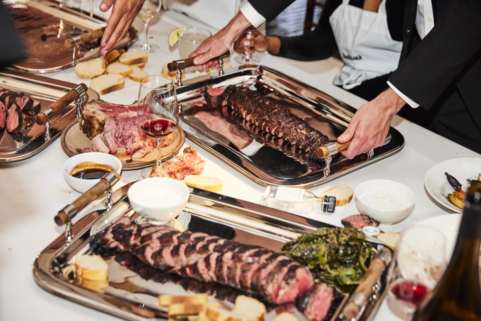 a waiter sets down a tray of beef on a table