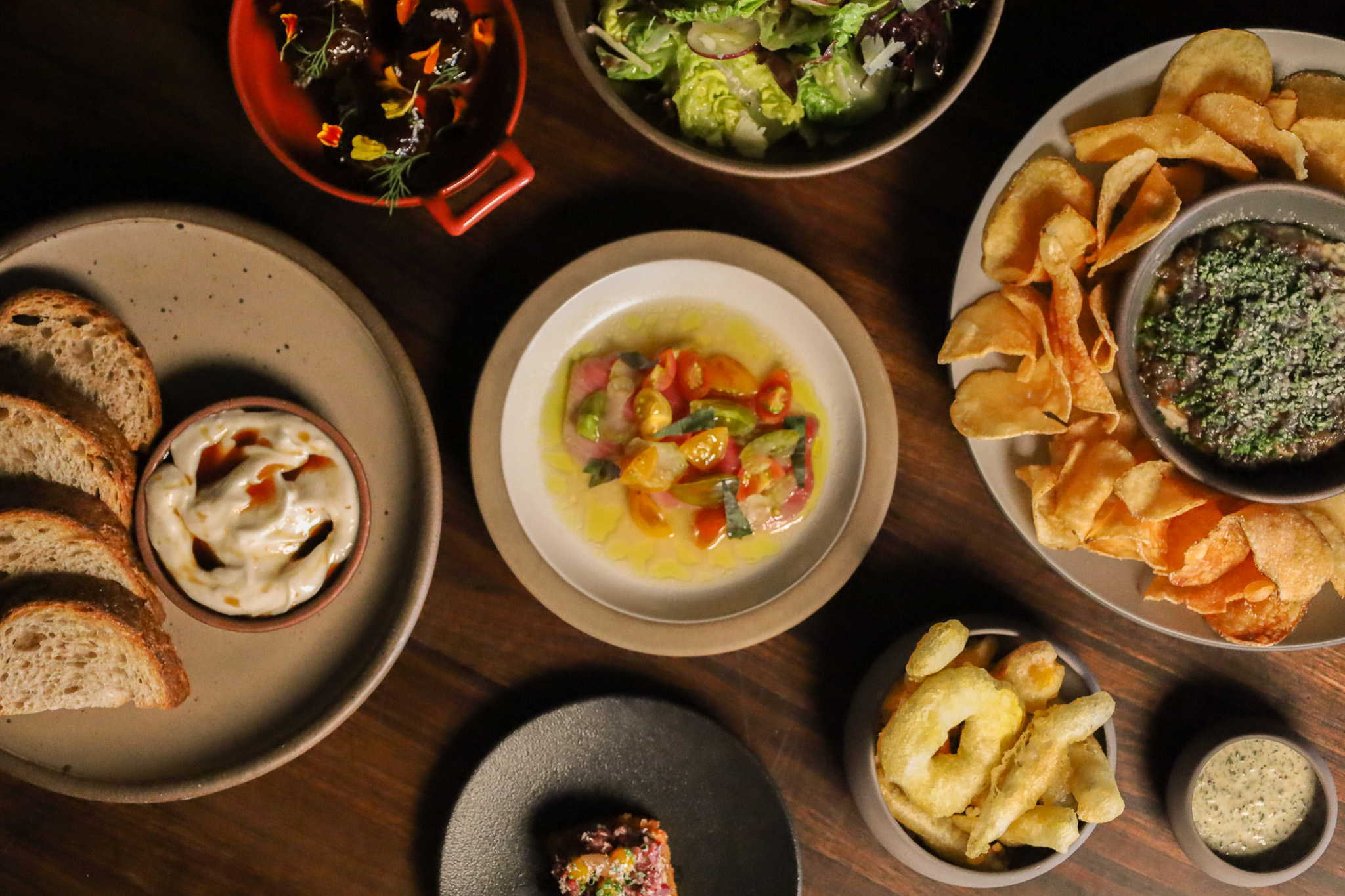 an array of food on round dishes on a brown table