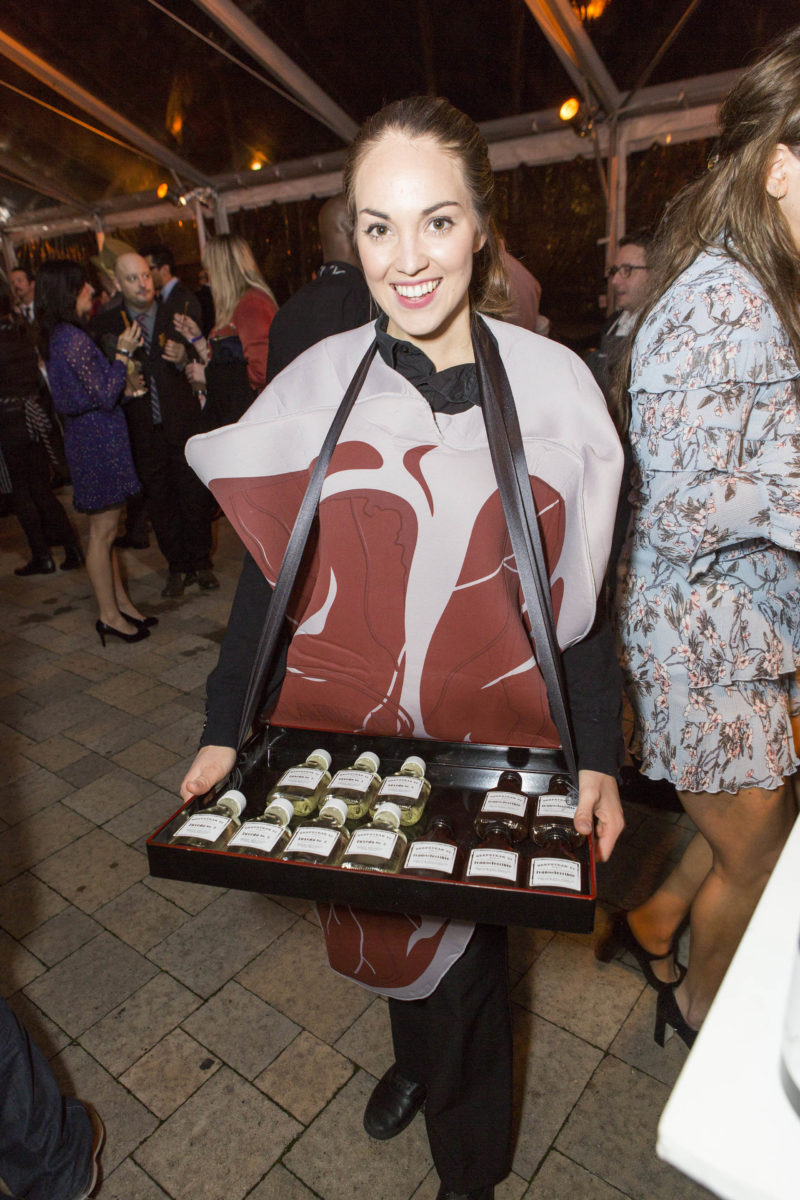 woman in steak costume holding out tray of liquor bottles
