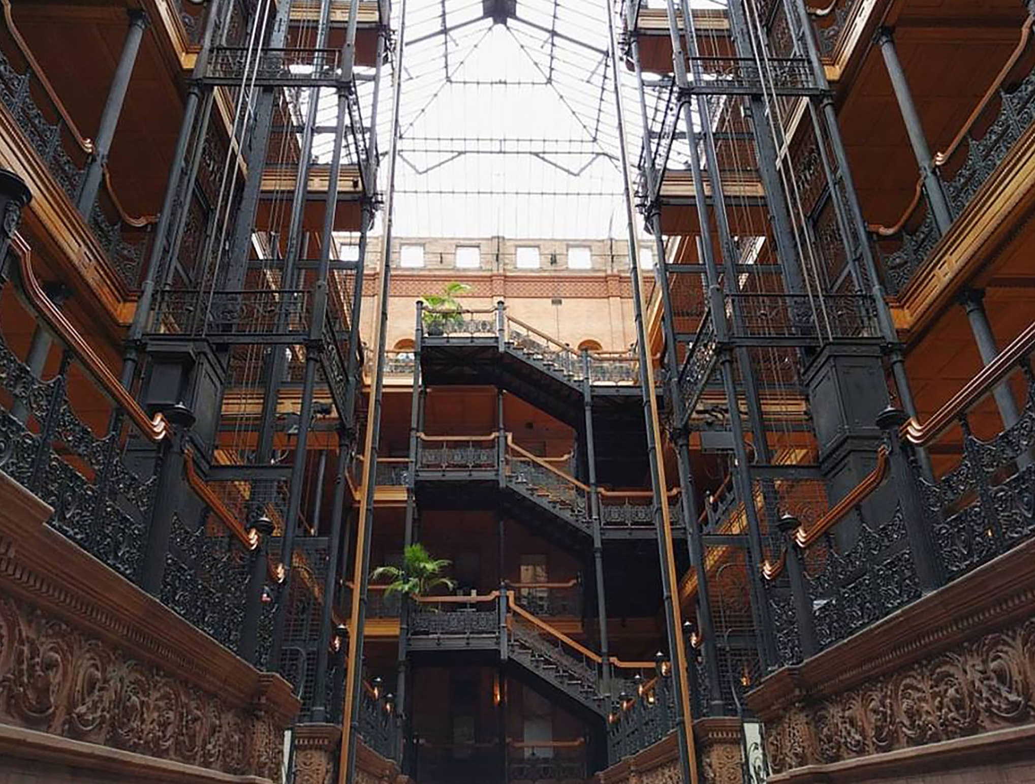indoor view of building architecture made up of elaborate iron railings and a glass ceiling