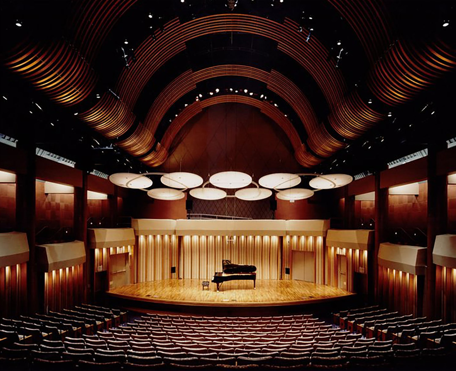 View from the back of an empty theatre with a piano in the middle of the stage