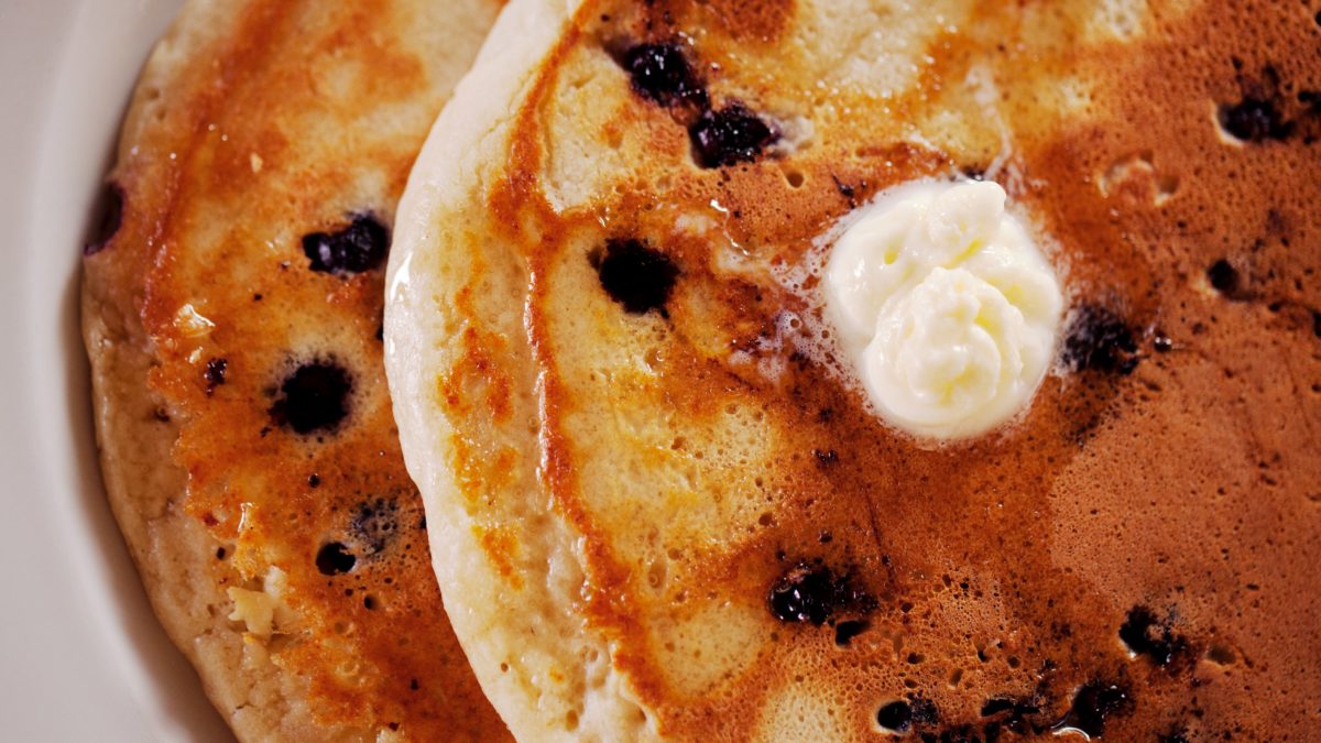 closeup of two blueberry pancakes with butter