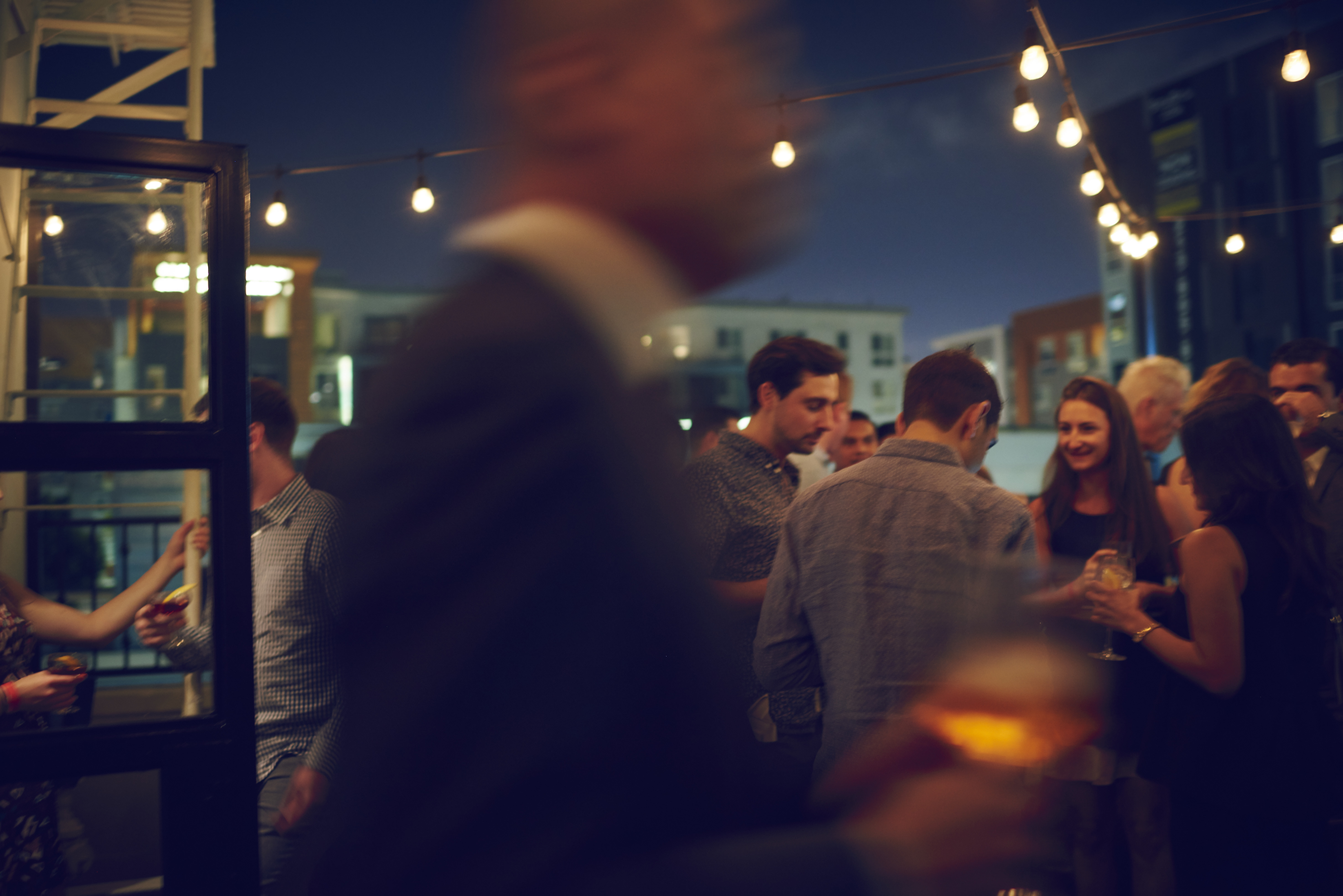 Crowd of people mingling at outdoor bar at night