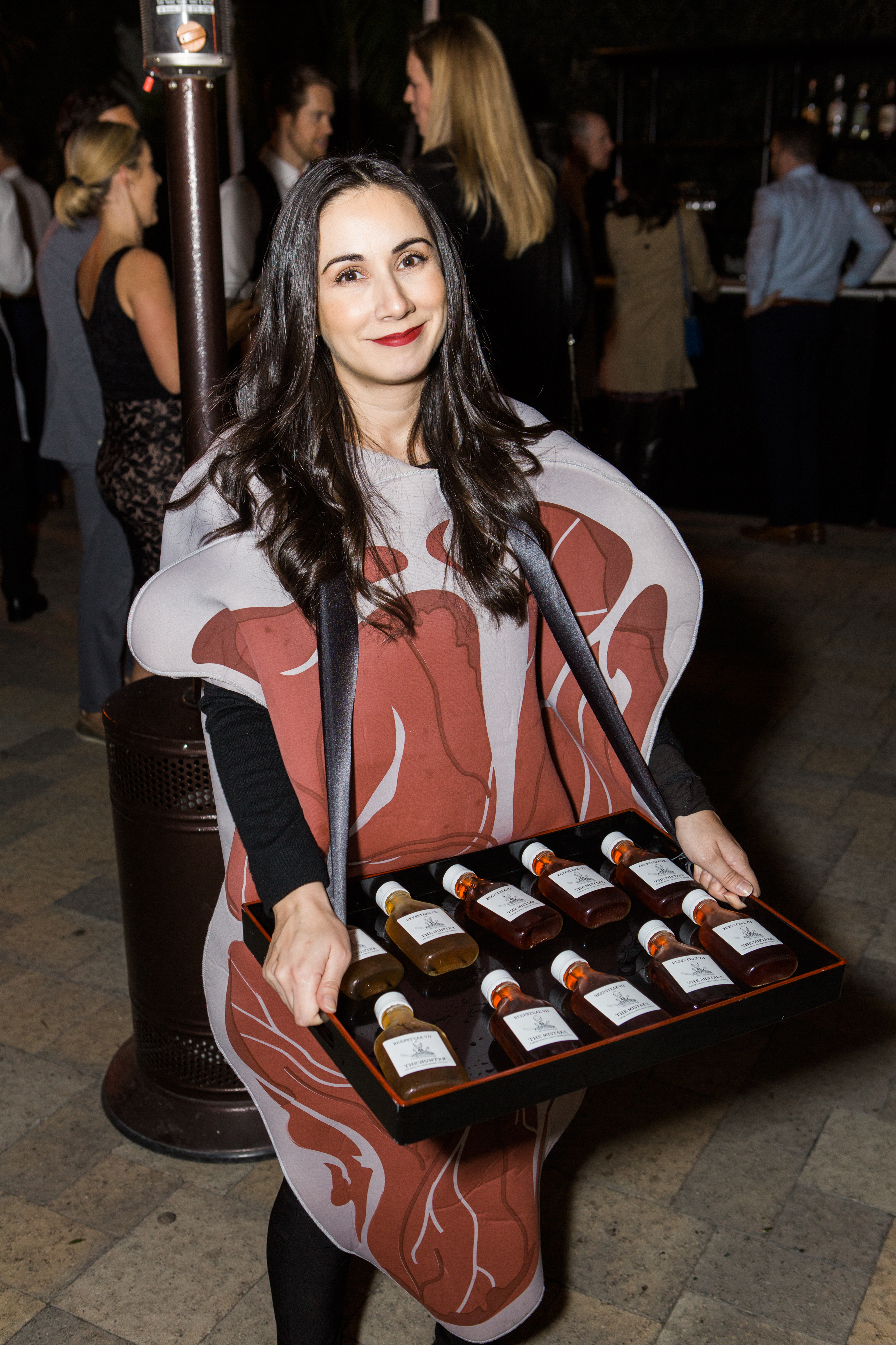 woman wearing steak costume and holding tray of whisky bottles