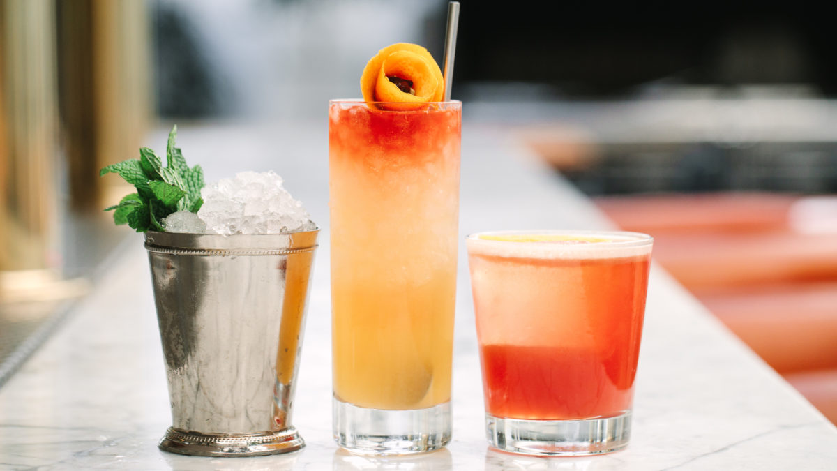 three different cocktails sitting on a marble bar top