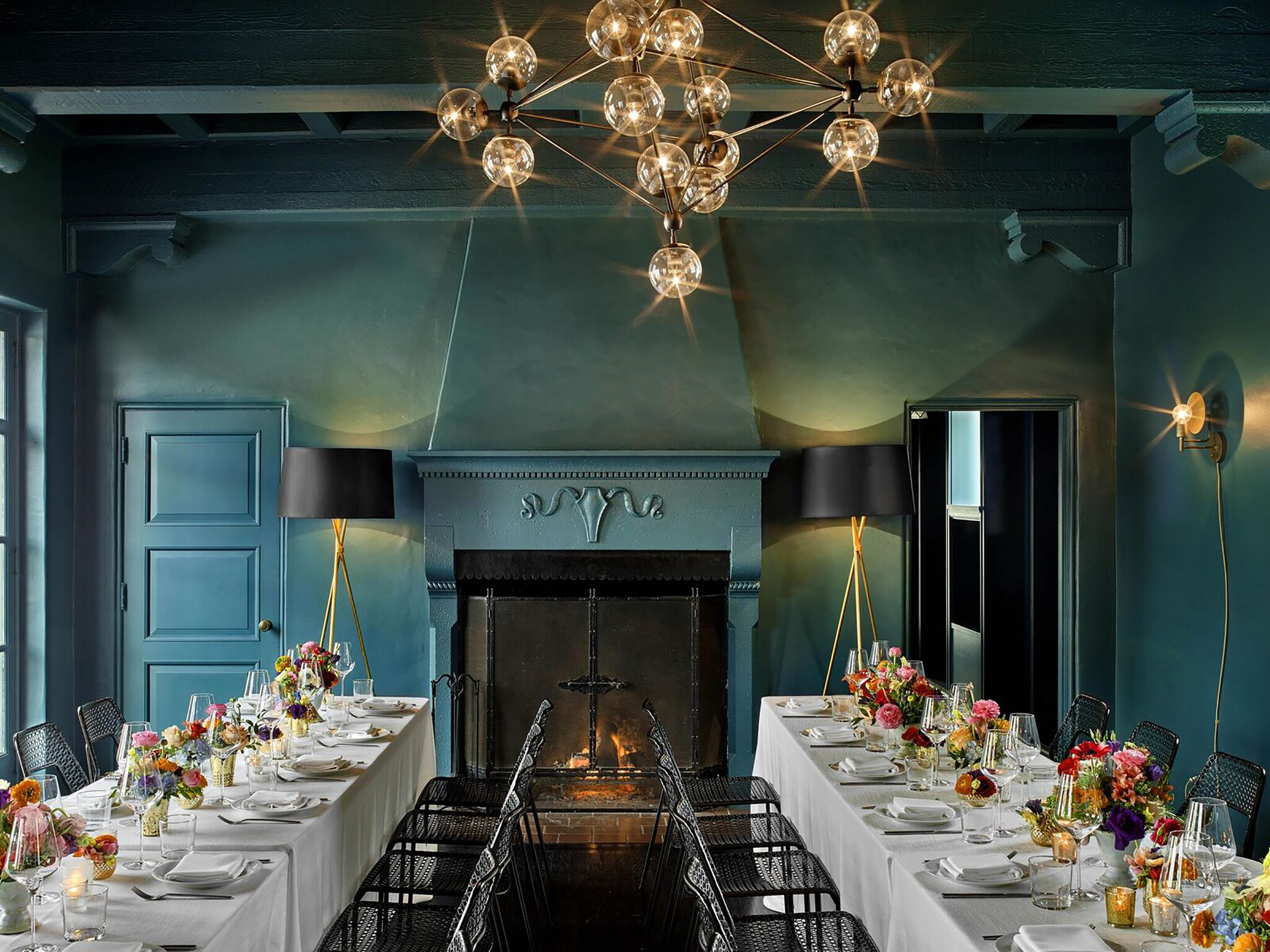 green room with gold lighting fixtures with two long tables in front of fireplace