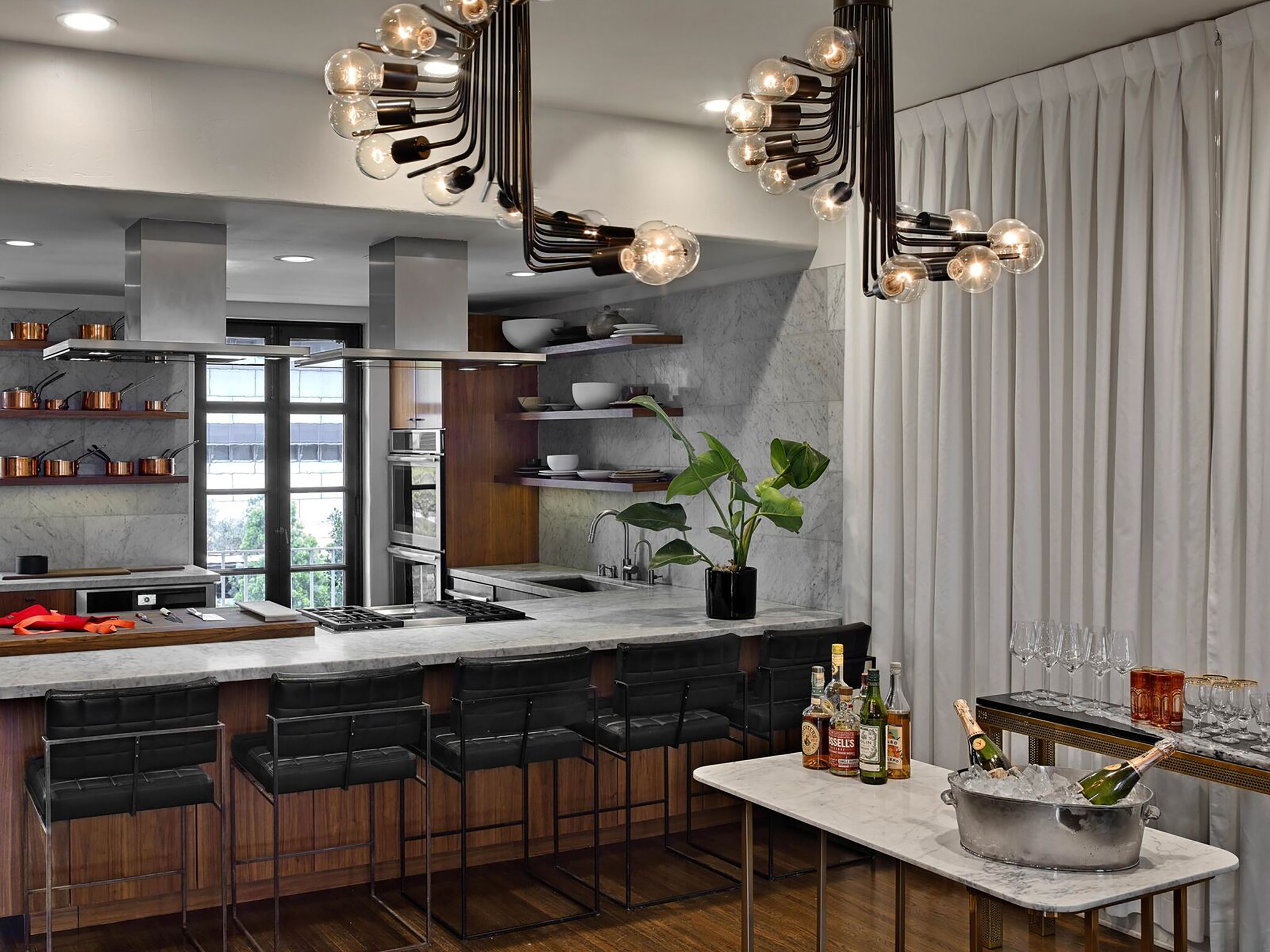 kitchen marble bar and black barstools with a small cocktail bar in front