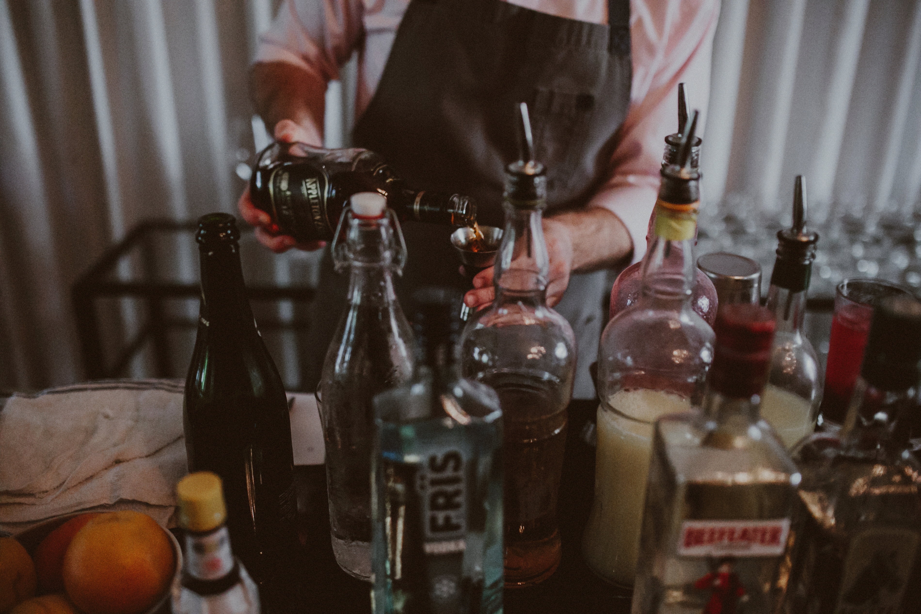A bartender poised with various liquors pouring a shot