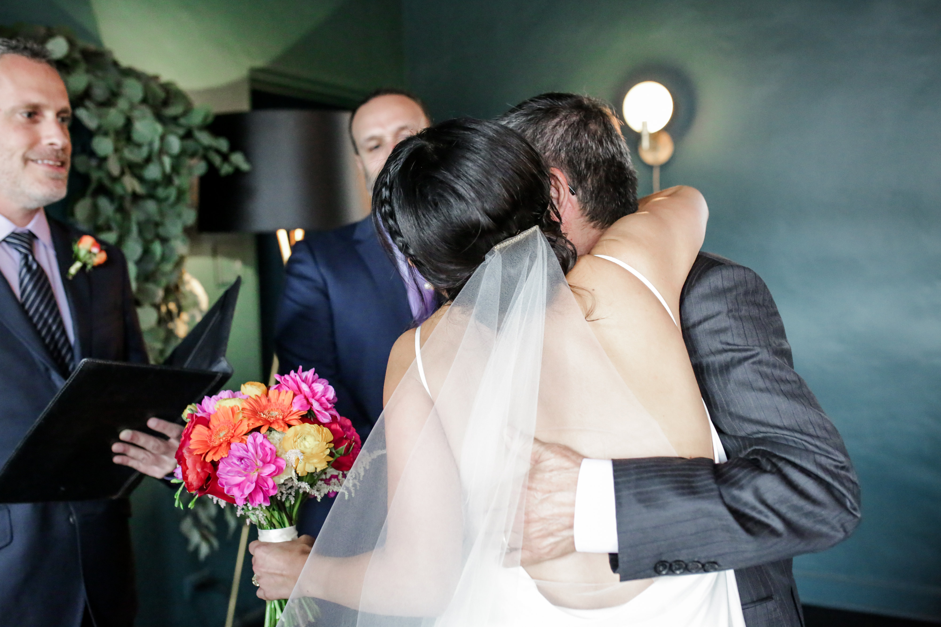 A bride and groom embracing as the officiant pronounces them married
