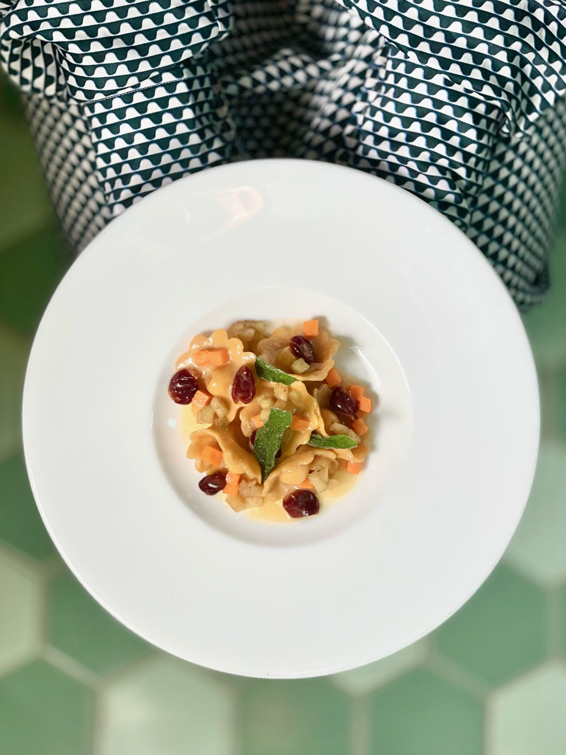 cappelletti pasta with cranberries being held by a woman in a funky dress on a green floor